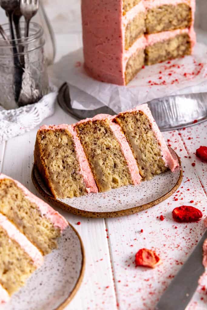 Slice of strawberry cake on a plate with a knife.