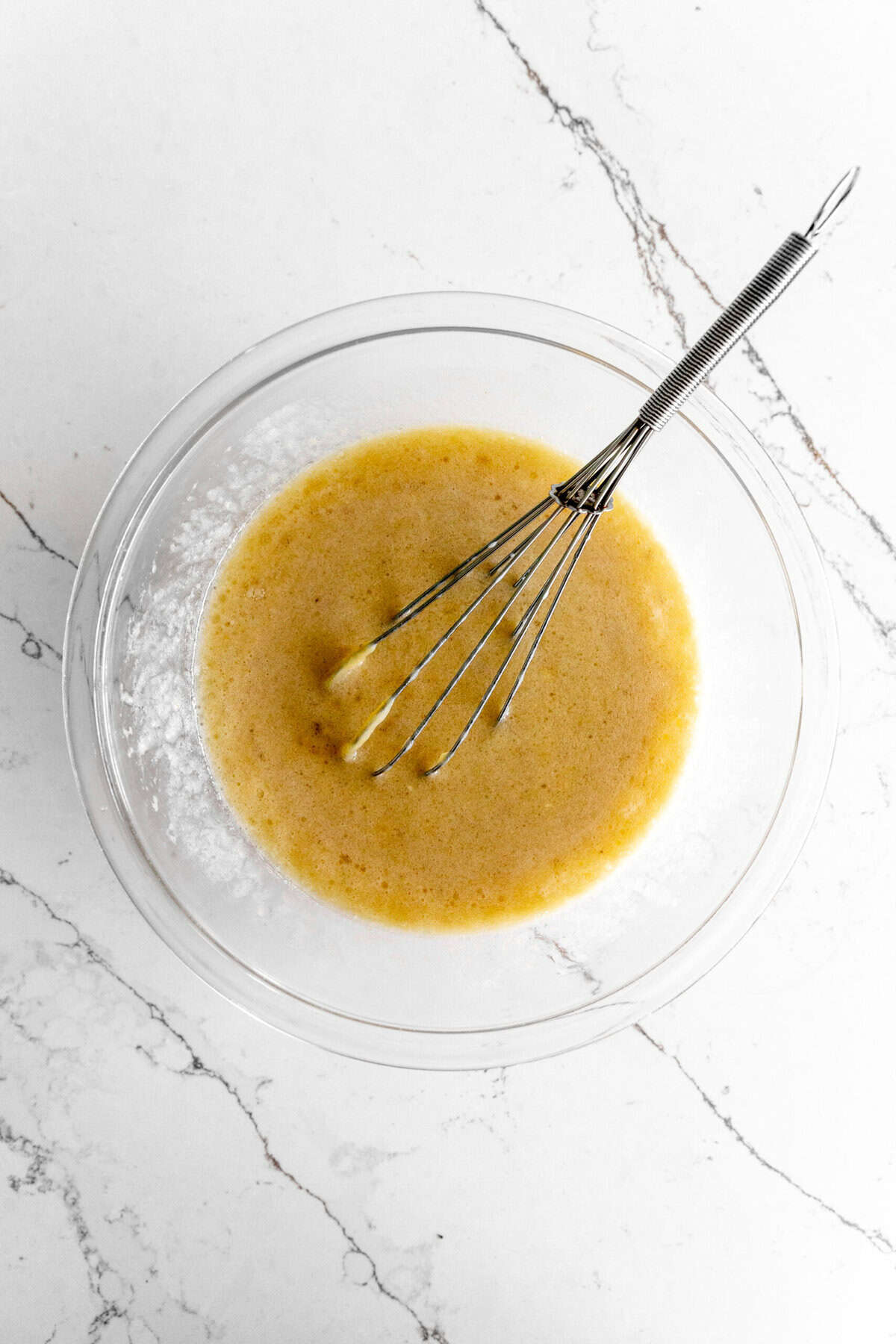 A bowl of mashed banana and milk with a whisk