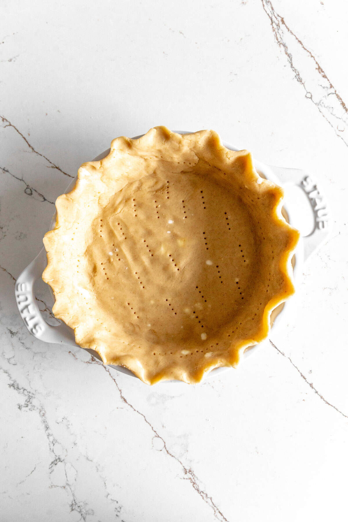 Unbaked piecrust in a white pie dish.