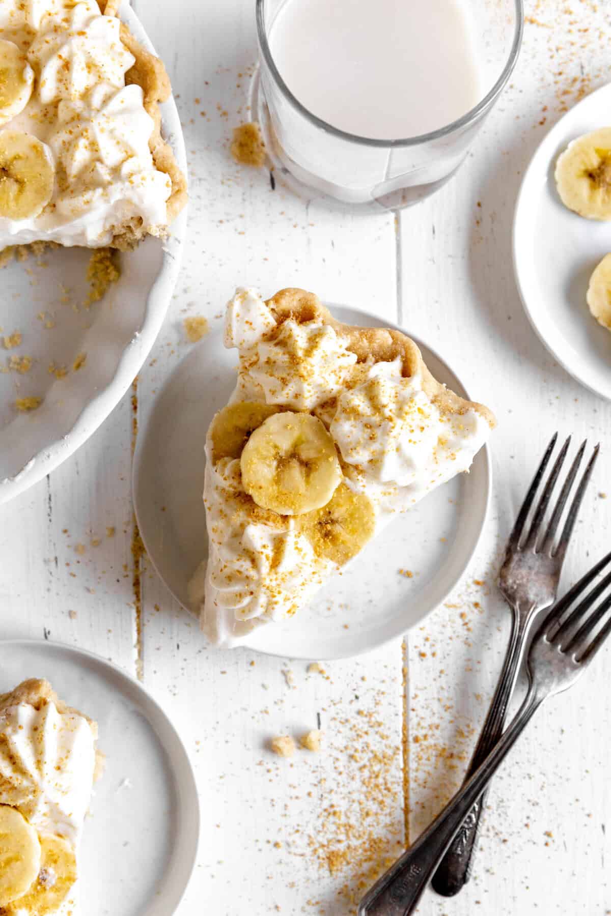 Slice of banana cream pie on a plate and two forks.