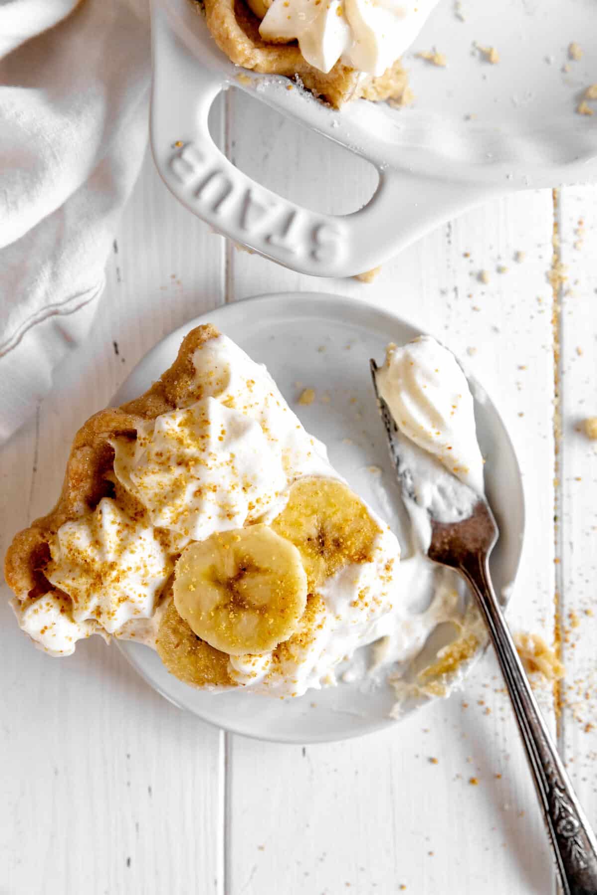 Fork cutting into a slice of banana cream pie.
