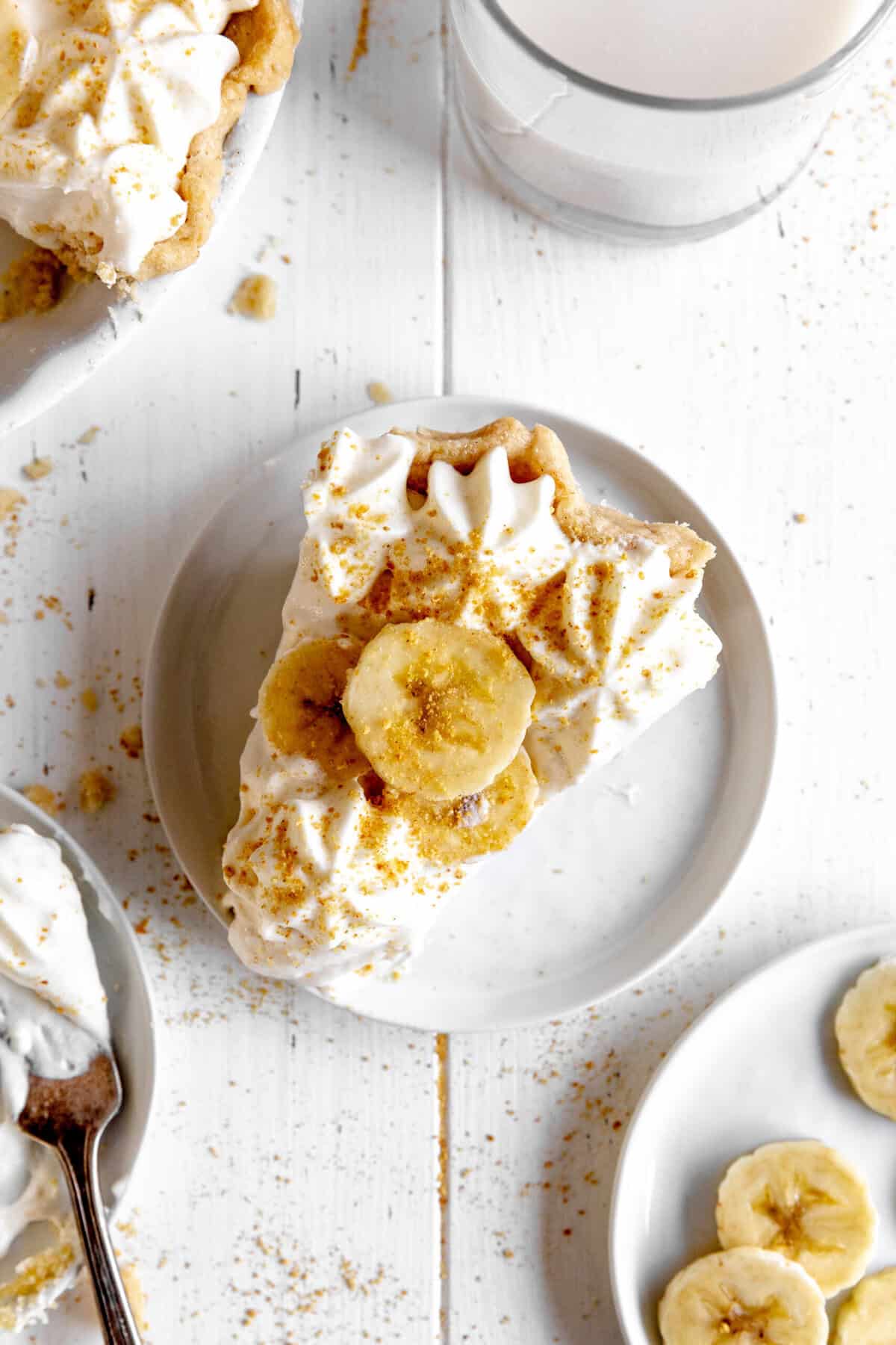 Slice of banana cream pie on a white plate and a plate of banana slices.
