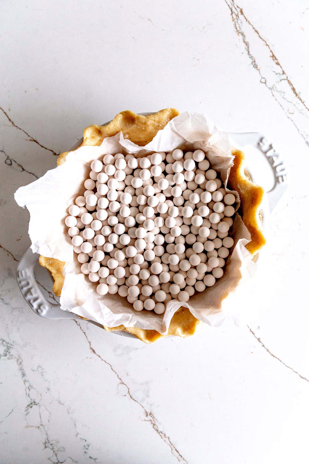 Unbaked piecrust filled with ceramic pie weights.