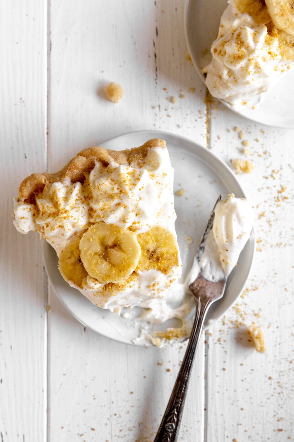 Fork cutting into a slice of banana cream pie.
