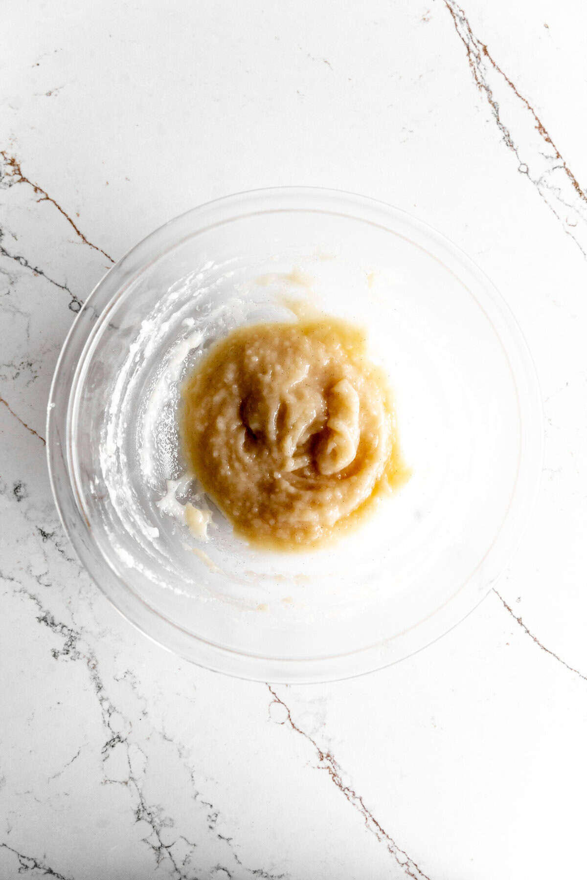 Vanilla pudding in a glass bowl on a marble counter.