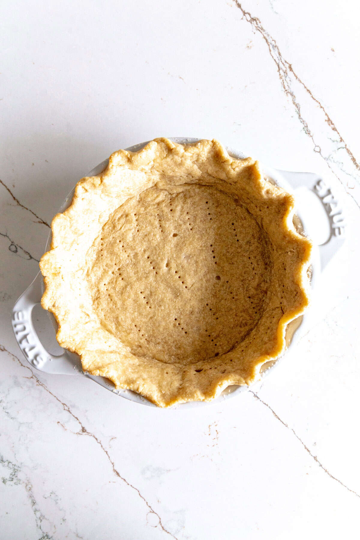 Baked piecrust in a white pie dish.