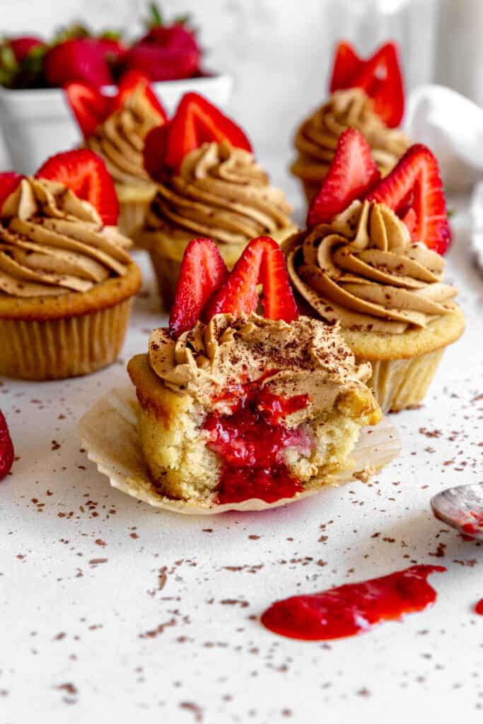 Strawberry jam oozing out of the center of a cupcake.