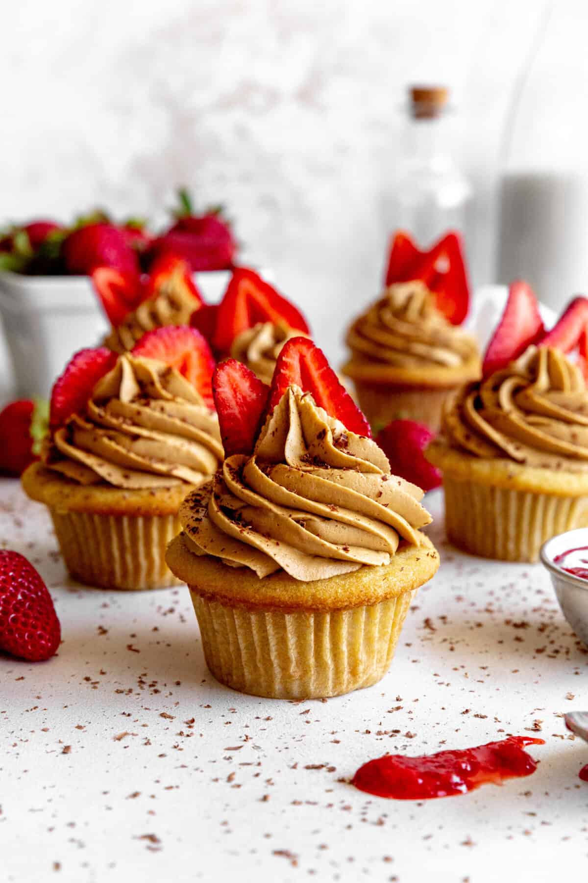 Strawberry tiramisu cupcakes, a basket of strawberries and a jug of milk.