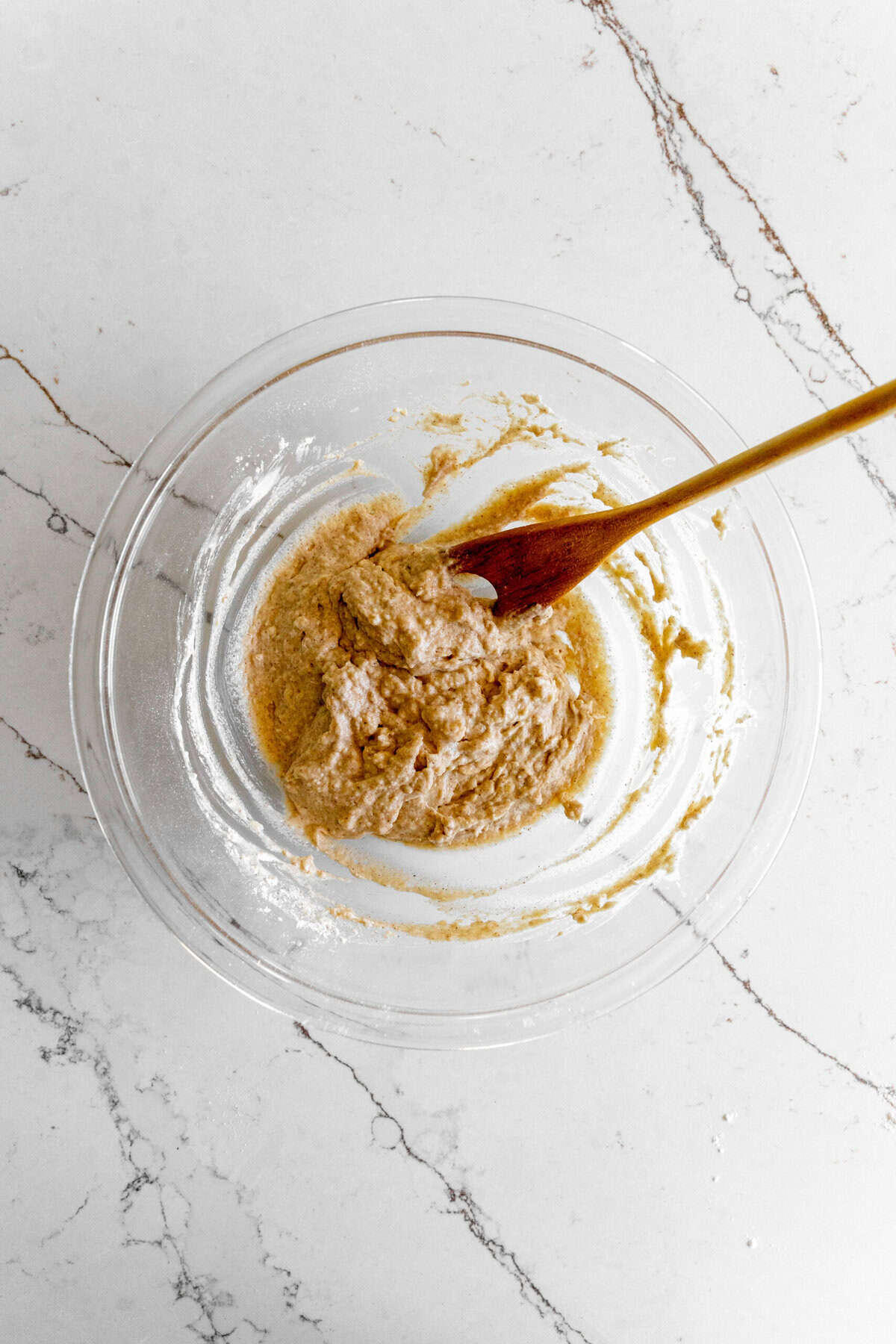 Cobbler dough in a glass bowl with a wooden spoon.