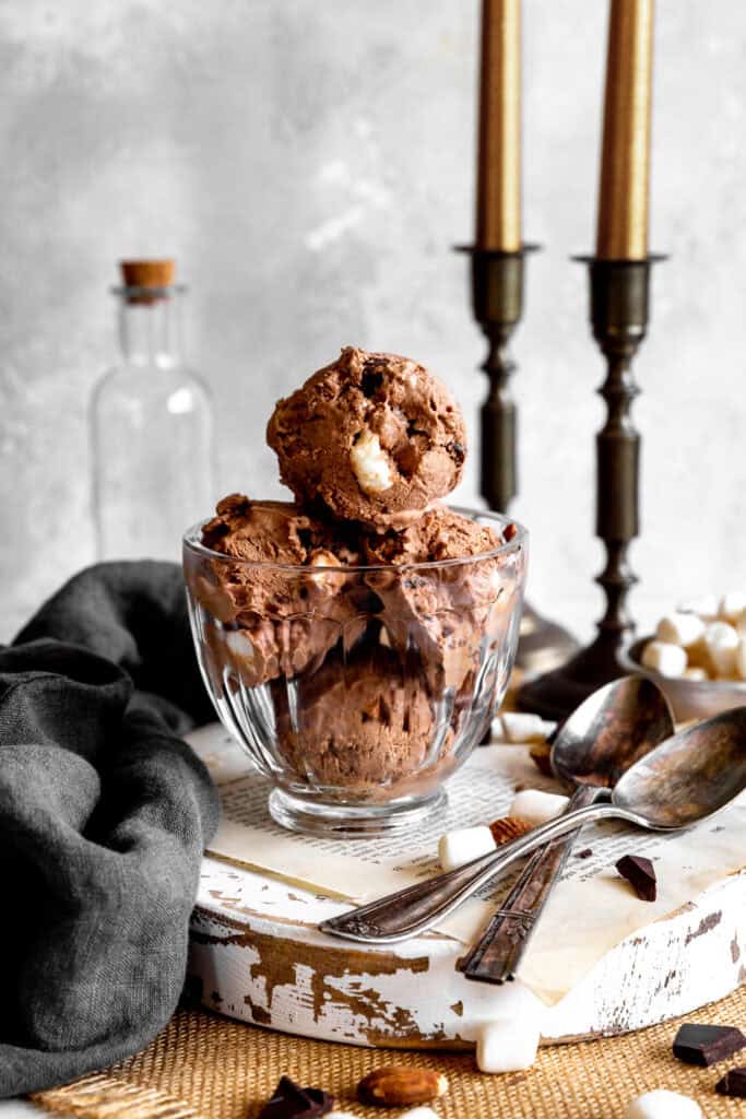 Glass dish of rocky road ice cream with two spoons.
