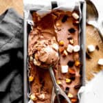 Ice cream scoop in a pan of rocky road ice cream.