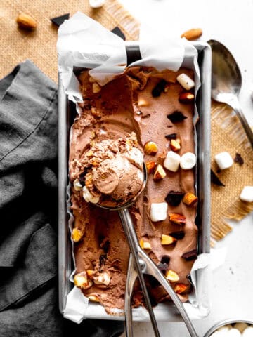 Ice cream scoop in a pan of rocky road ice cream.