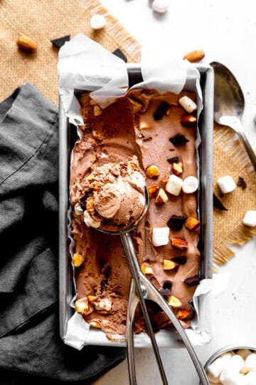 Ice cream scoop in a pan of rocky road ice cream.