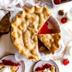 Strawberry rhubarb pie with slices missing and a dish of fresh strawberries.