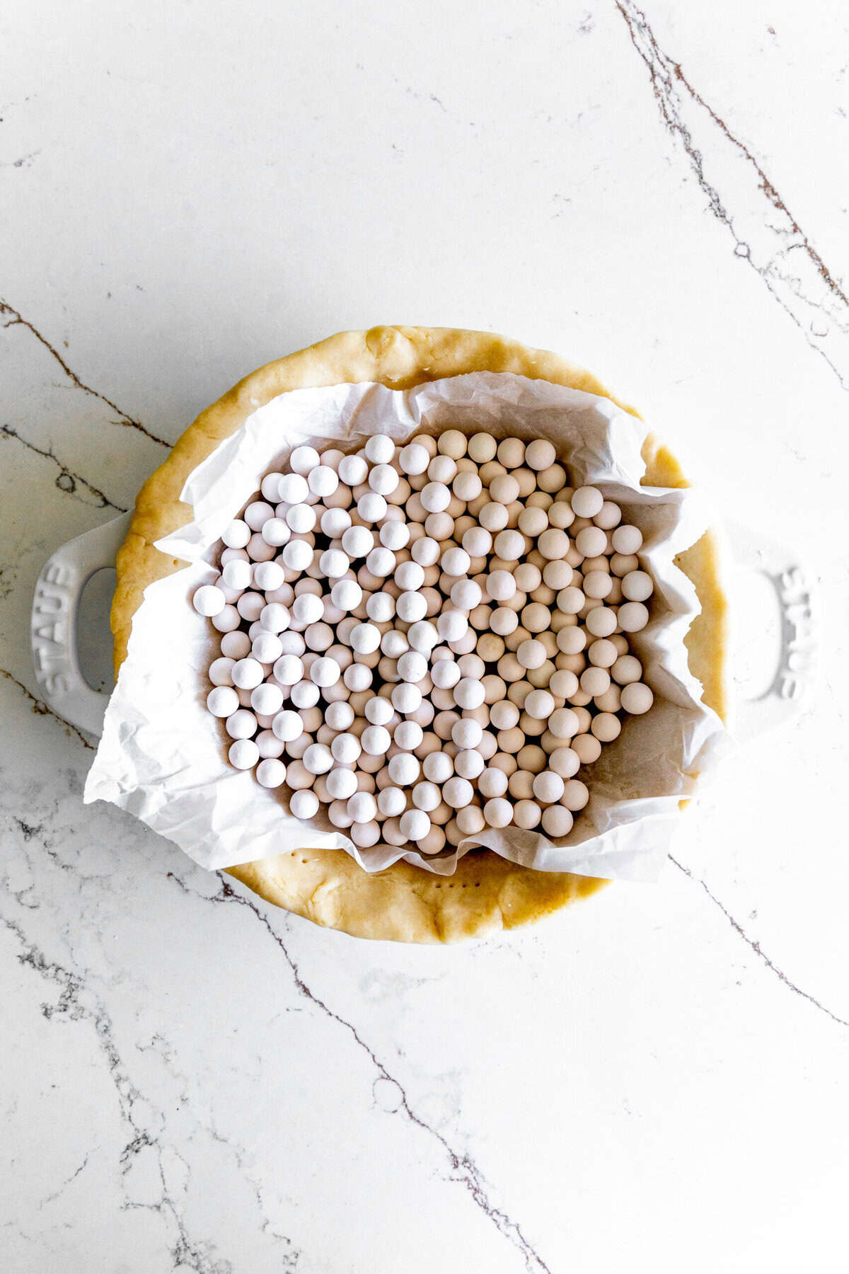 Par baked pie crust filled with ceramic pie weights.