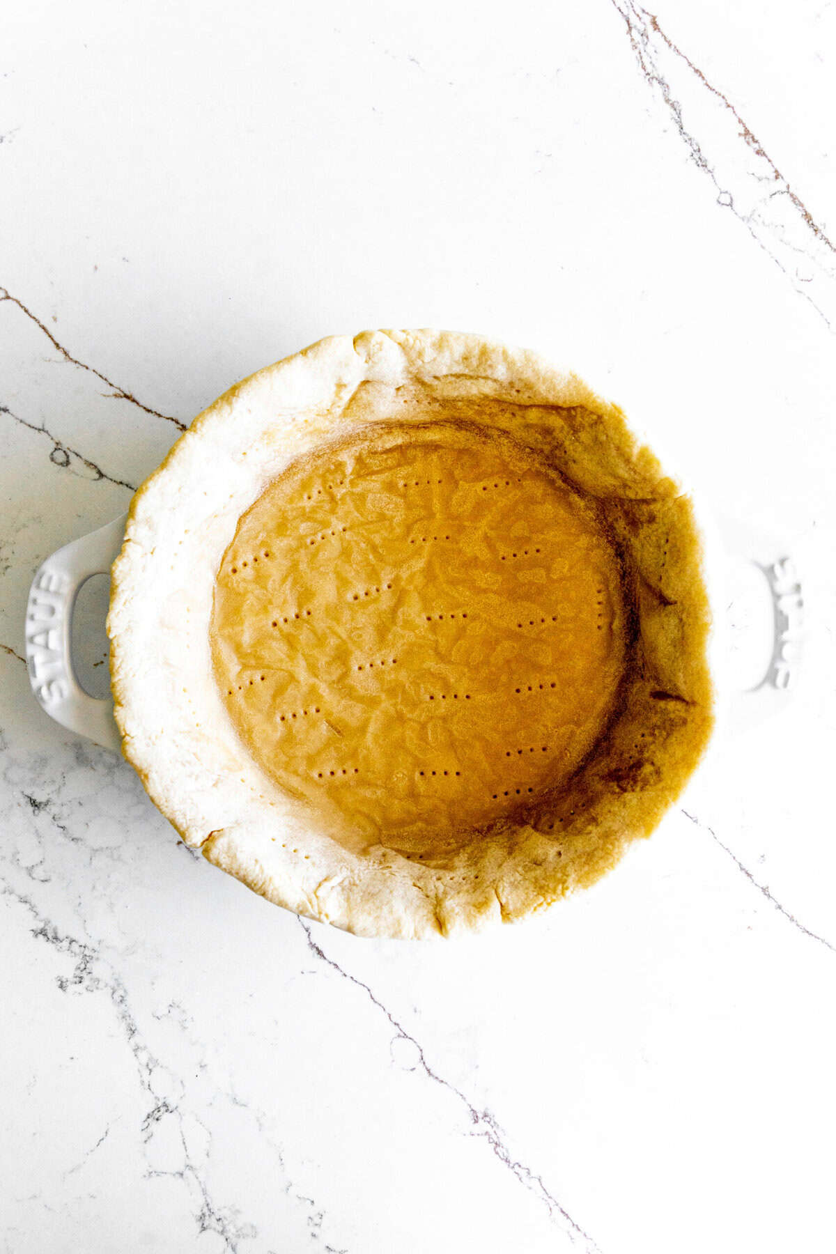 Par baked pie crust in a white pie dish.