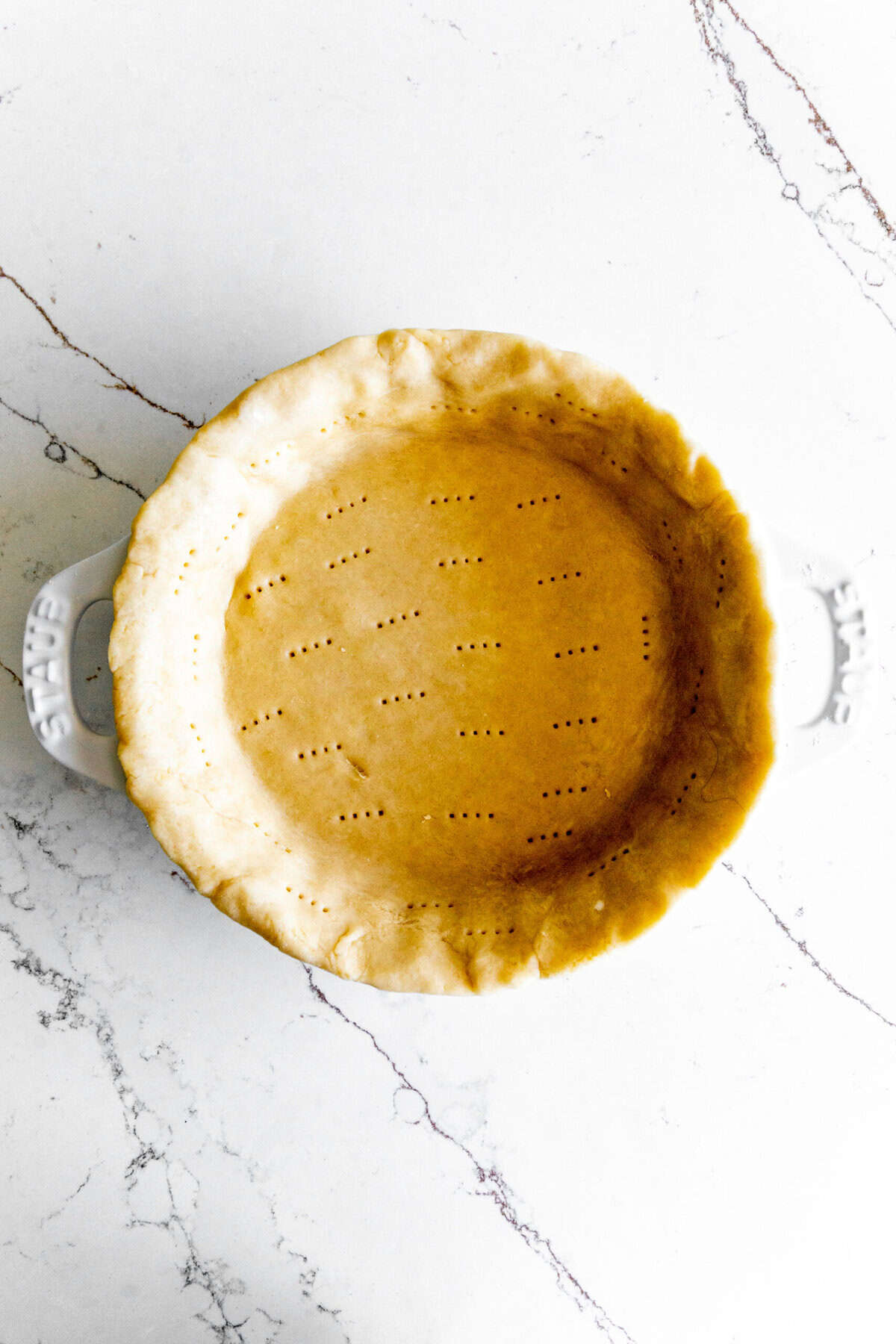 Unbaked pie crust in a white pie dish.