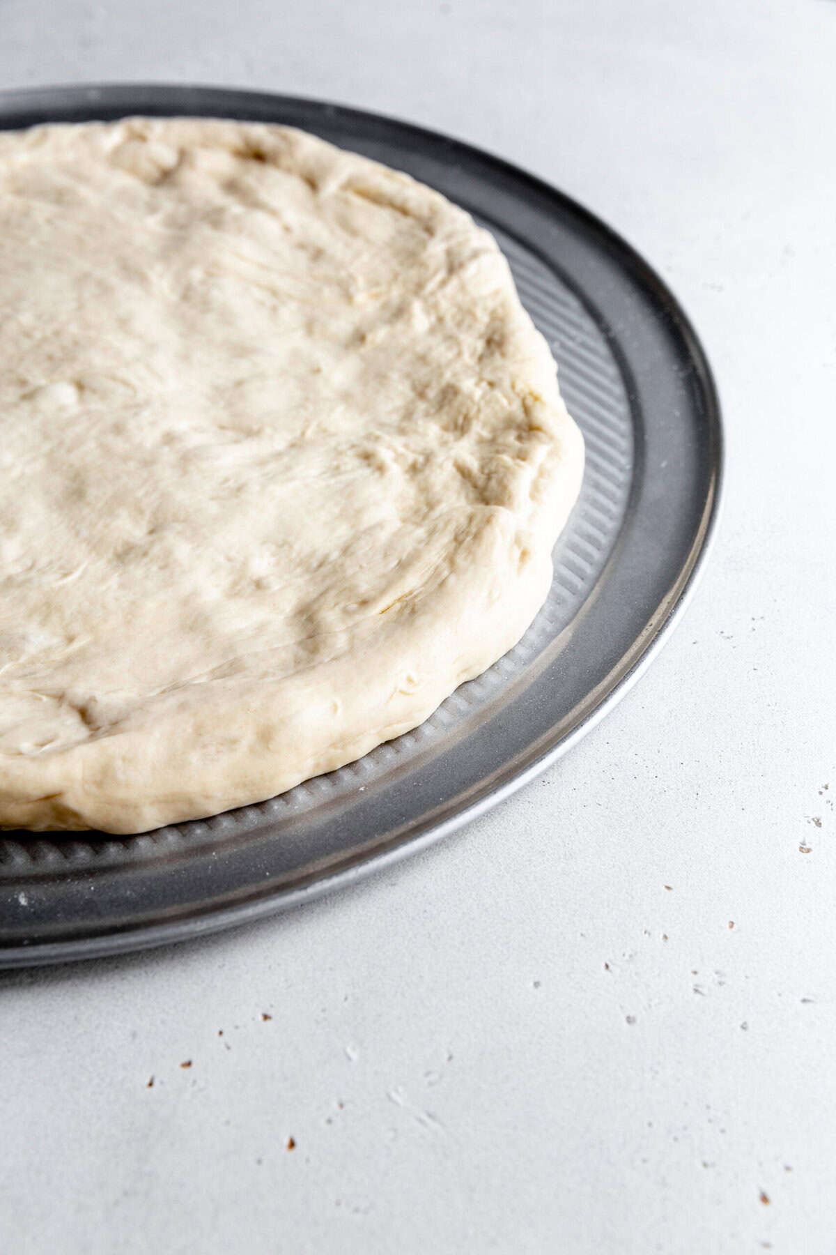 Crimped pizza dough on a pizza pan.