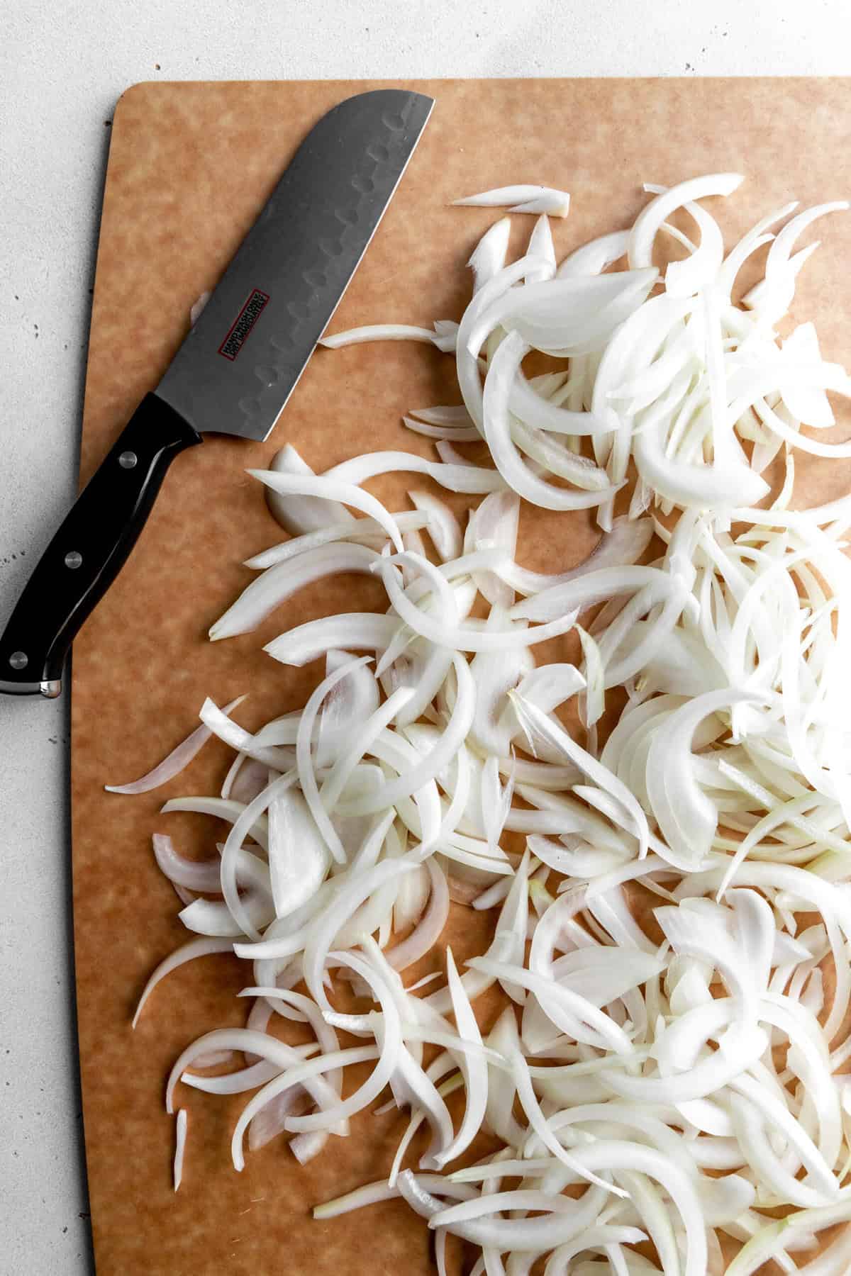 Sliced onions on a cutting board with a knife.