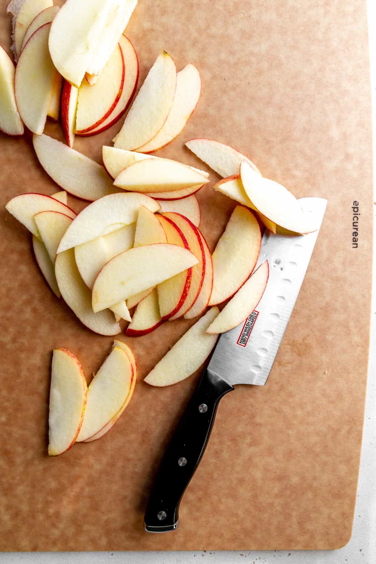 Sliced apples on a cutting board with a knife.
