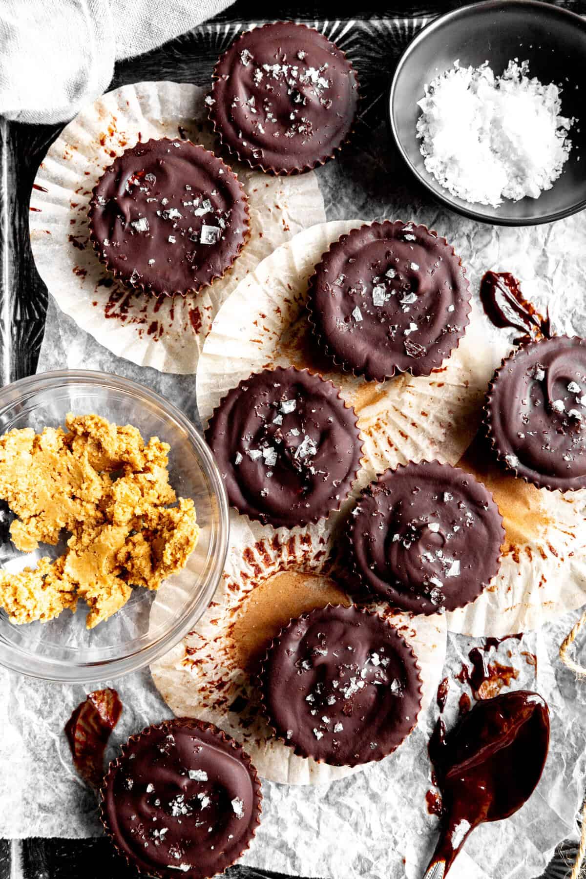 Chocolate peanut butter cups, a bowl of flaky salt and a spoon covered in melted chocolate.