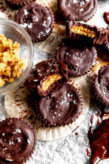 Peanut butter cup with a bite taken out of it and a bowl of peanut butter.