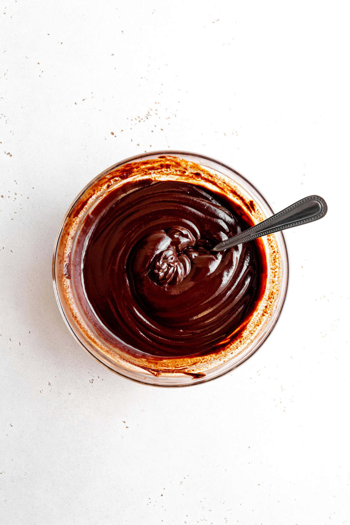 Melted chocolate in a glass bowl with a spoon.