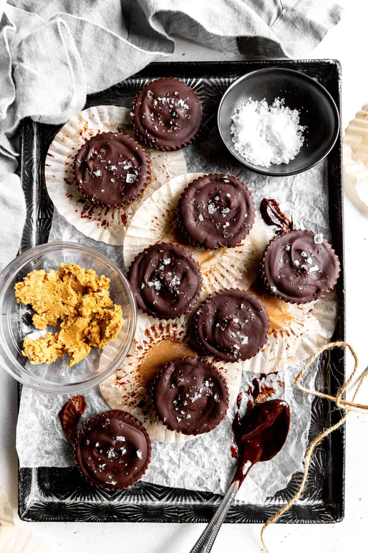 Chocolate peanut butter cups, a bowl of flaky salt and a spoon covered in melted chocolate.