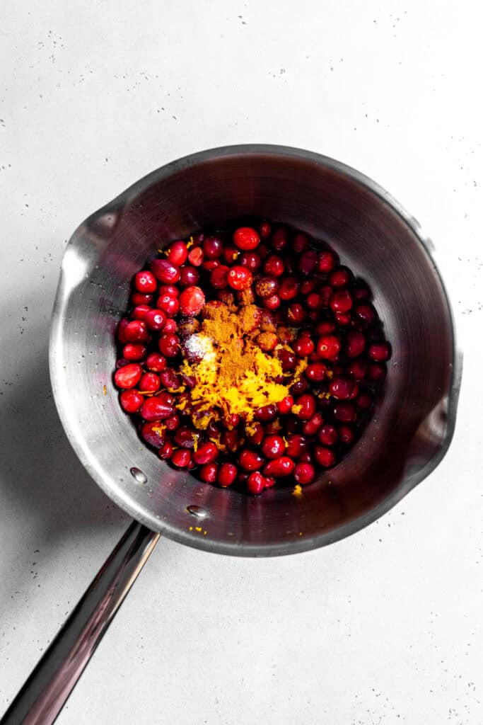 Cranberries, spices and orange zest in a pot.