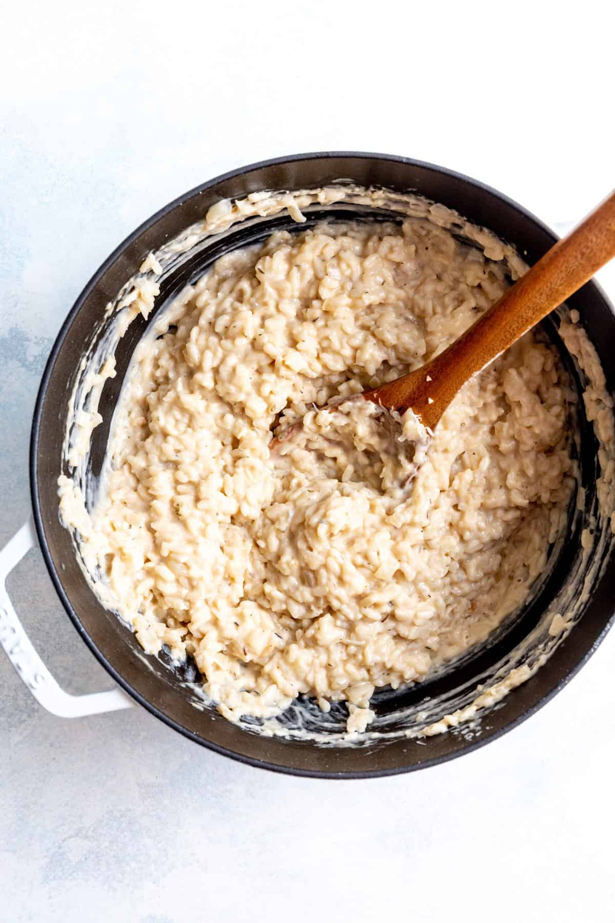 Wooden spoon in a pot of cooked garlic white wine risotto.