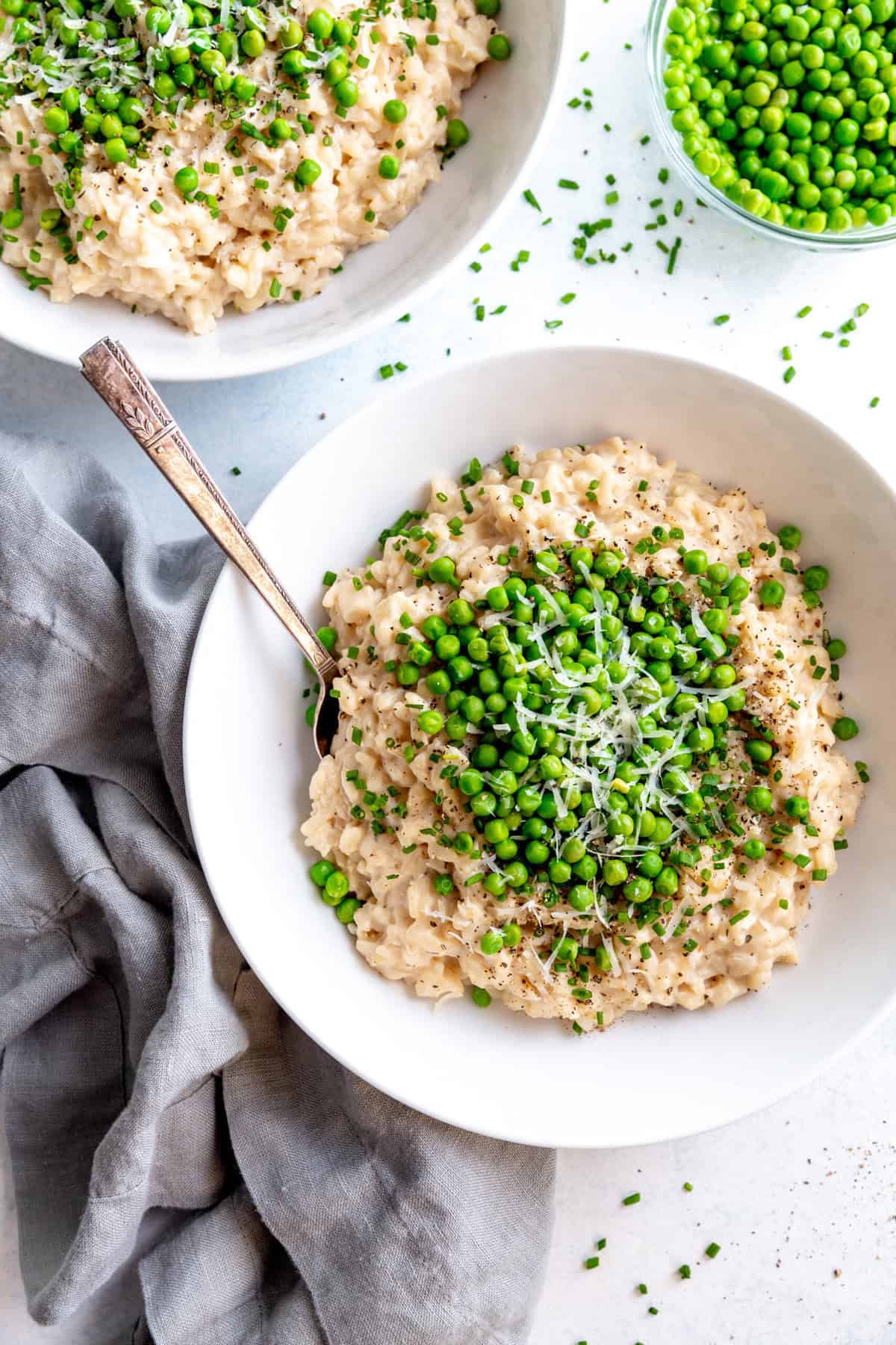 Two bowls of risotto and a small bowl of peas.