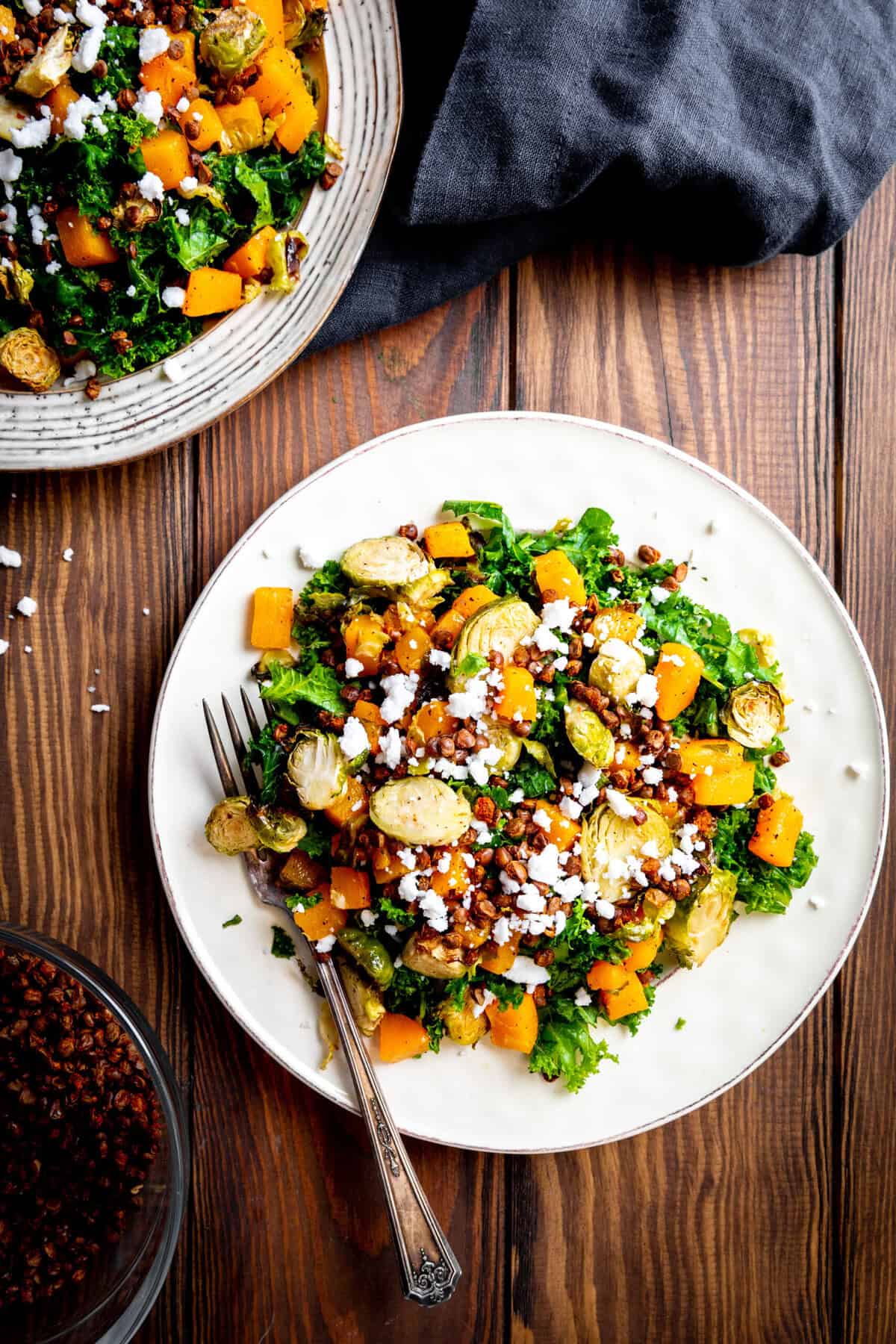 Kale butternut squash salad on a white plate with a fork.