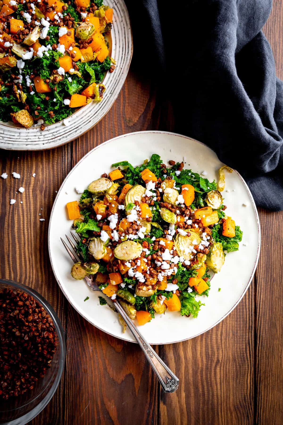 Kale butternut squash salad on a white plate with a fork.