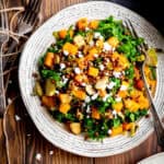 Fork digging into a plate of kale butternut squash salad.