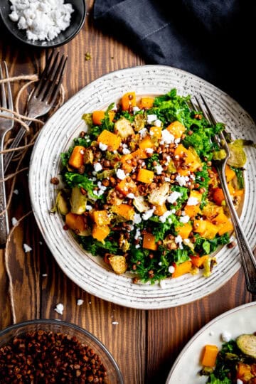 Fork digging into a plate of kale butternut squash salad.