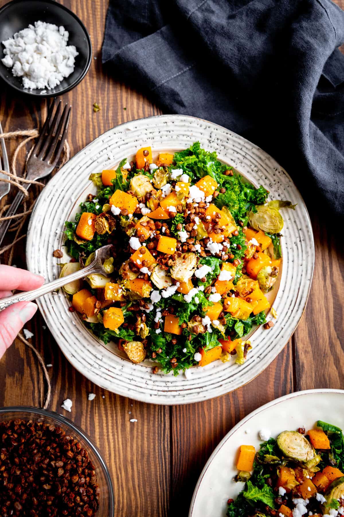 Hand holding a fork digging into a butternut squash salad.