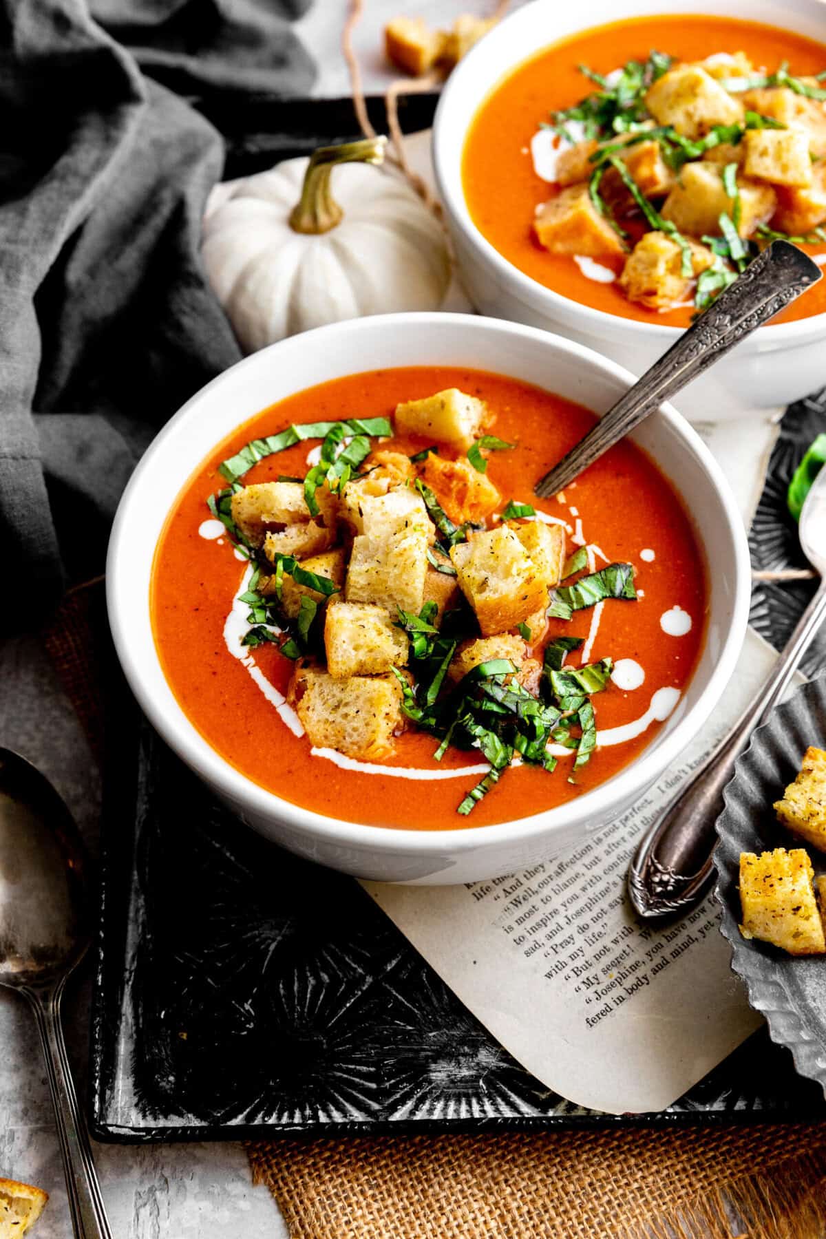 Spoon dipping into a bowl pf pumpkin tomato soup on a tray.