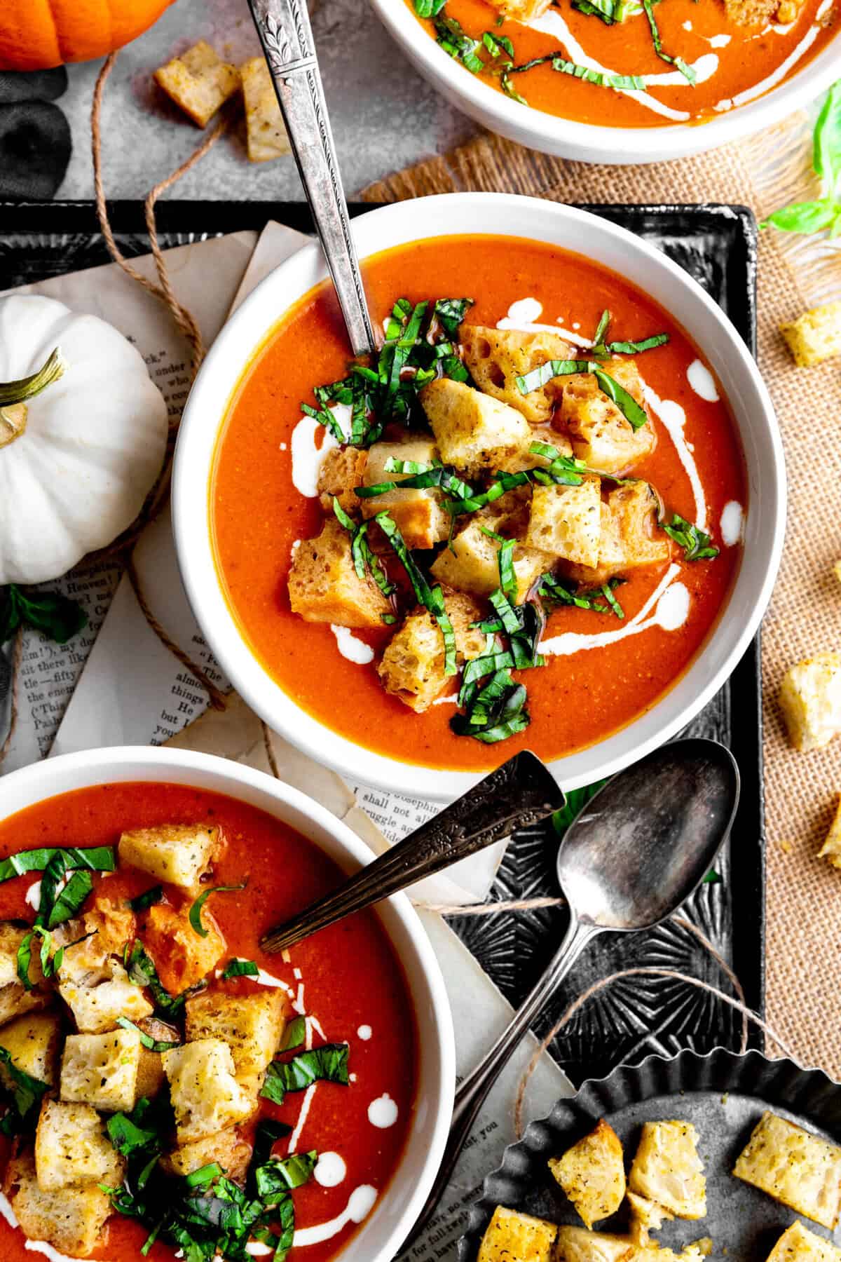 Pumpkin tomato soup in bowls with spoons.