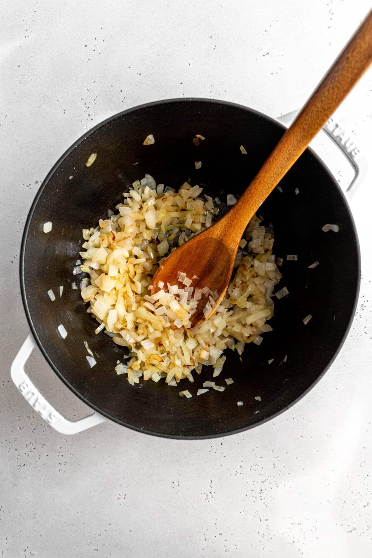 Sautéed onions in a pot with a wooden spoon.