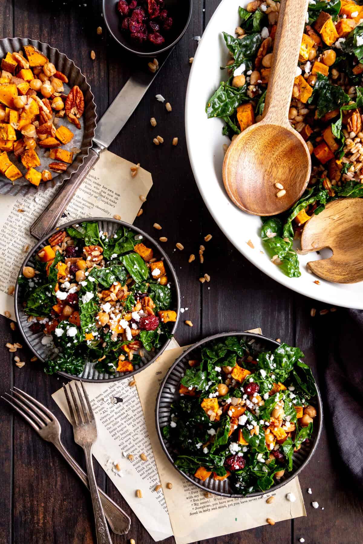 Large bowl of roasted sweet potato salad with tongs and two plates with salad.
