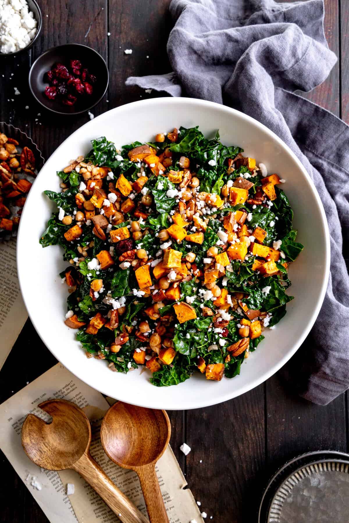 Kale salad with sweet potatoes in a white bowl, a linen napkin and a gray napkin.
