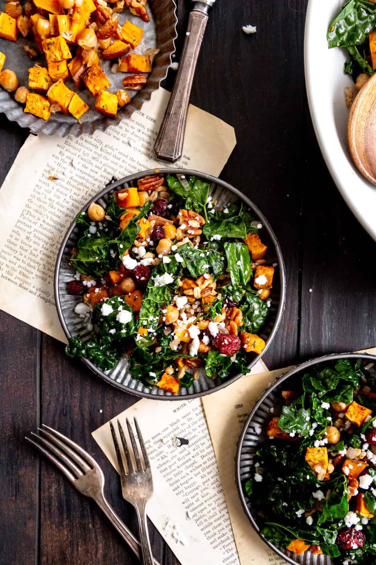Two metal plates with kale sweet potato salad.