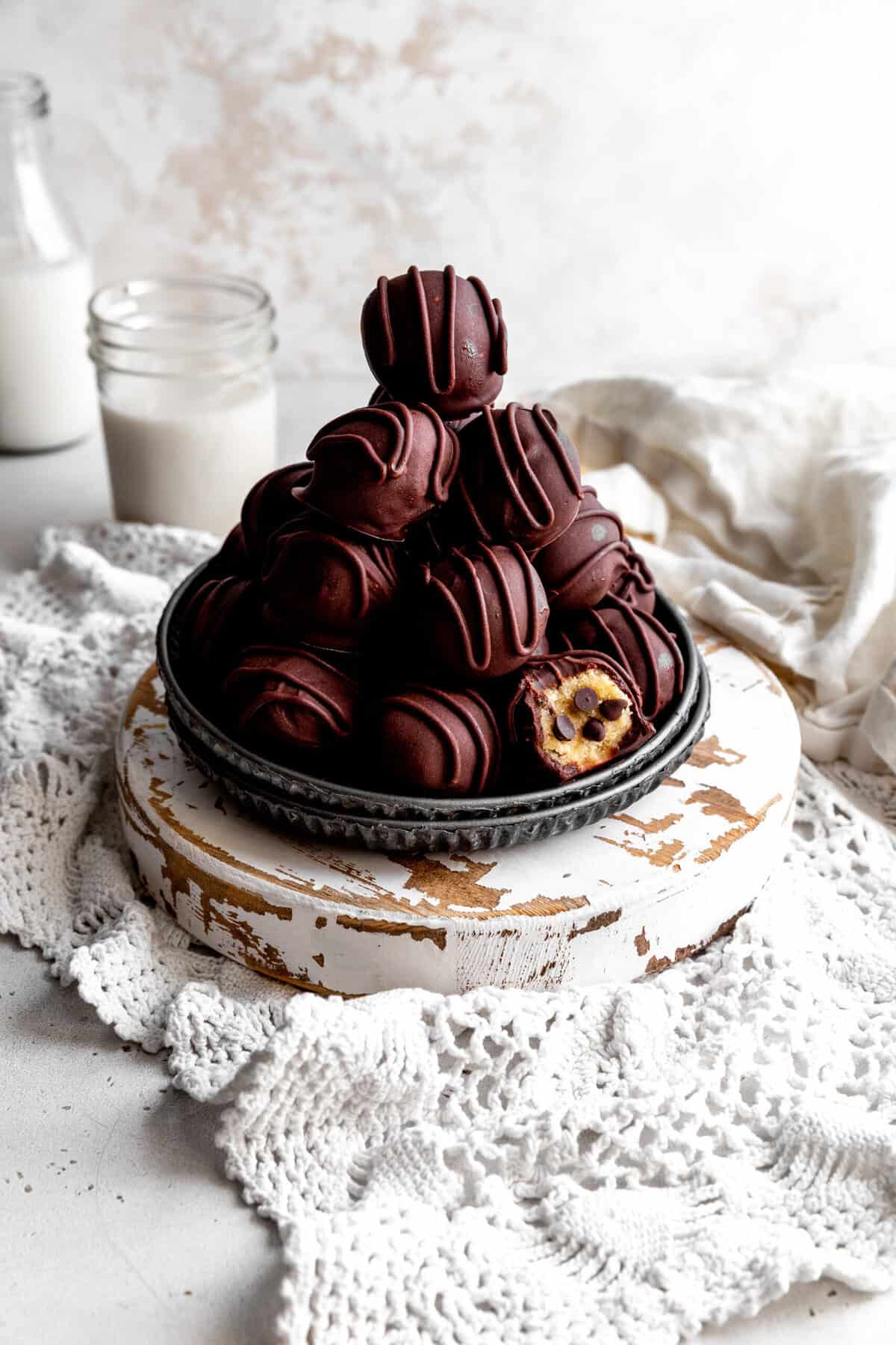 Stack of cookie dough bites, a white linen napkin and a glass of milk.