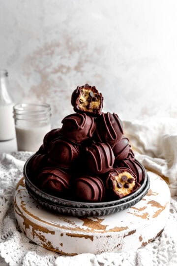 Cookie dough bite with a bite taken out of it topping a stack of more candies.