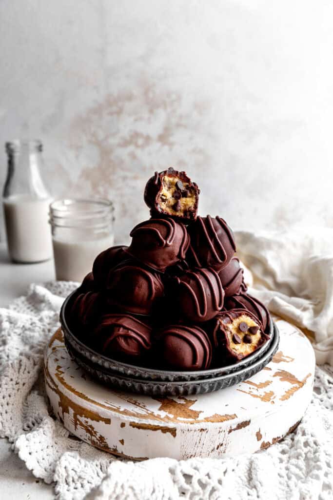 Cookie dough bite with a bite taken out of it topping a stack of more candies.