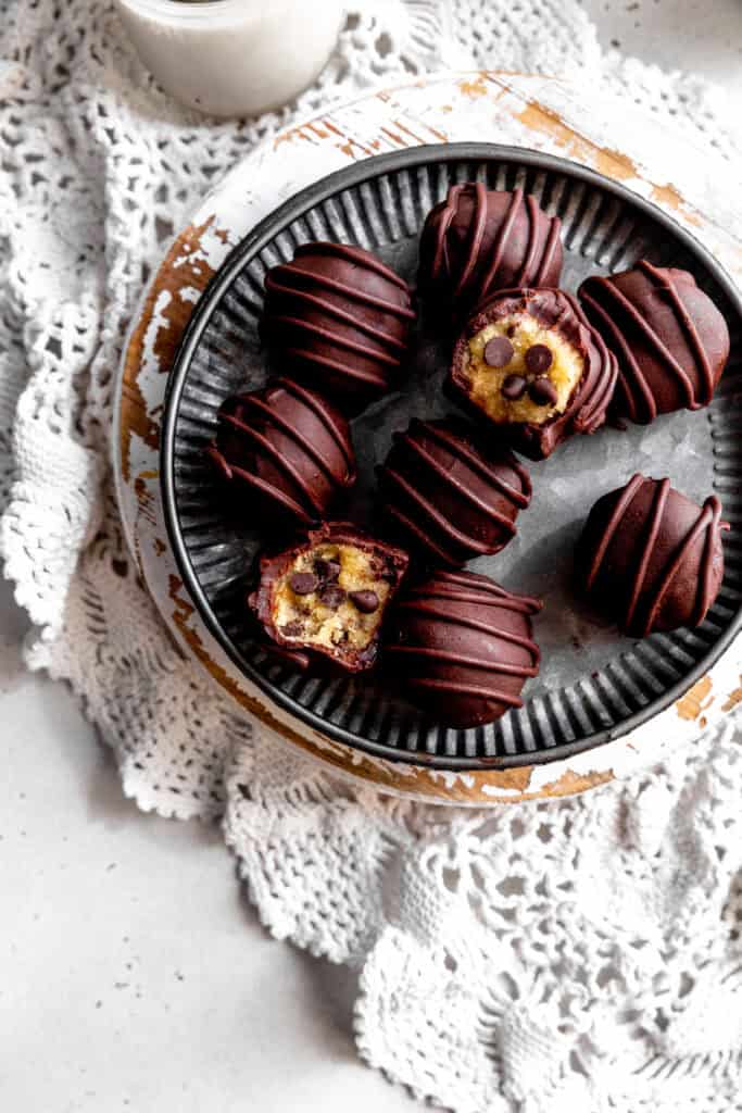 Half-eaten cookie dough bites on a metal plate and a glass of milk.