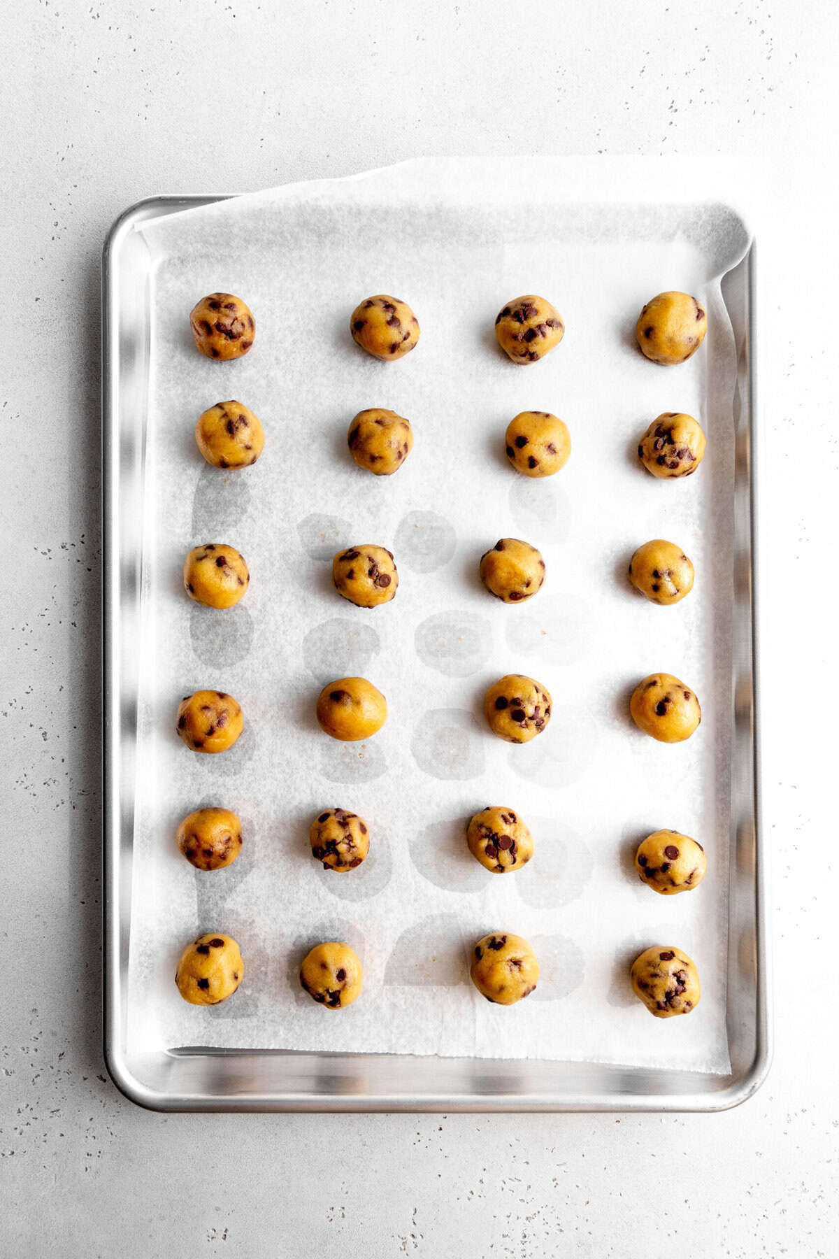 Uncoated cookie dough bites on a baking sheet.