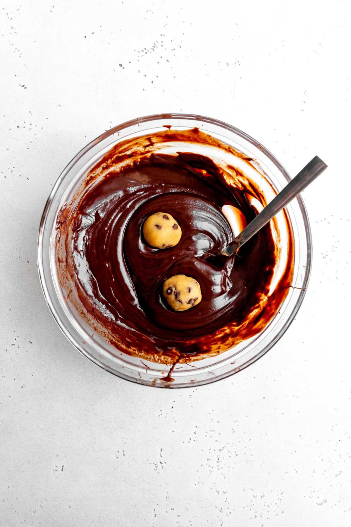 Cookie dough balls in a bowl of melted chocolate.
