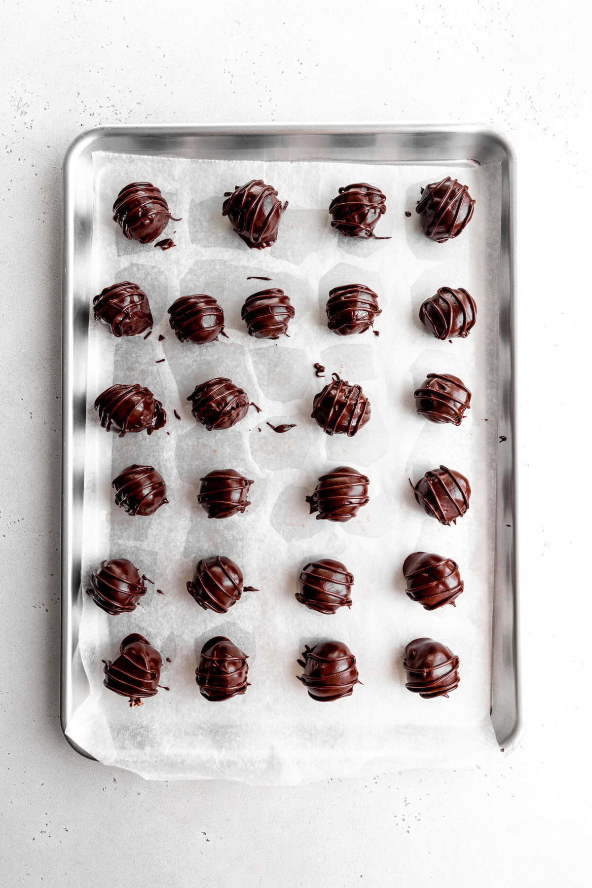 Coated, unset cookie dough bites on a baking sheet.