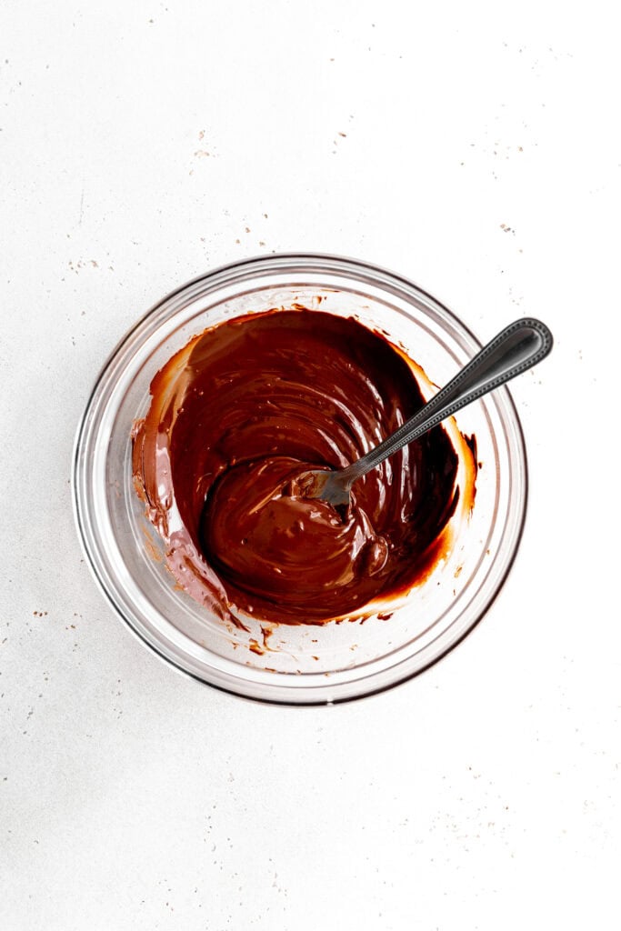 Melted chocolate in a glass bowl with a spoon.